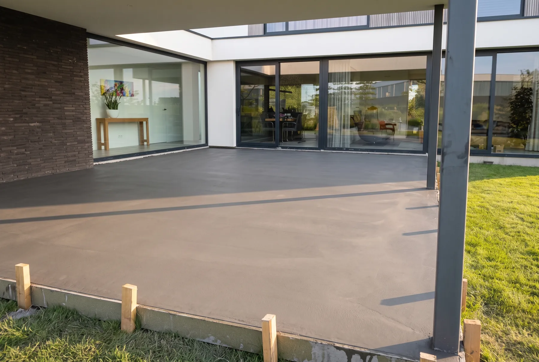 Nieuwe gevlinderde betonvloer onder een overkapping, in laag avondlicht