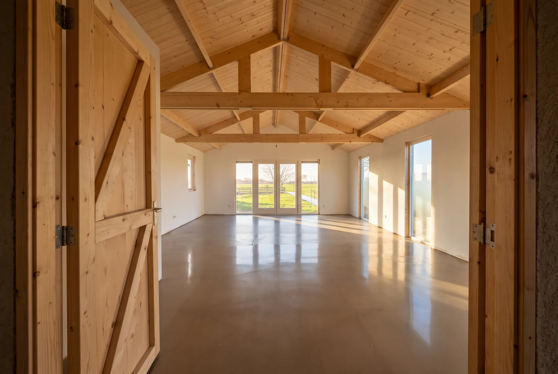 Nieuwe woning met open houten spanten en een glanzende vloer, in laag zonlicht